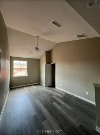 an empty room with wooden floor closet and windows