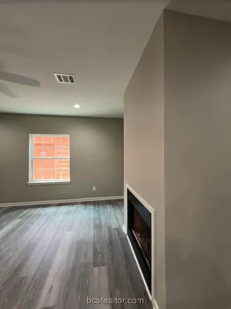 a view of empty room with wooden floor and fireplace