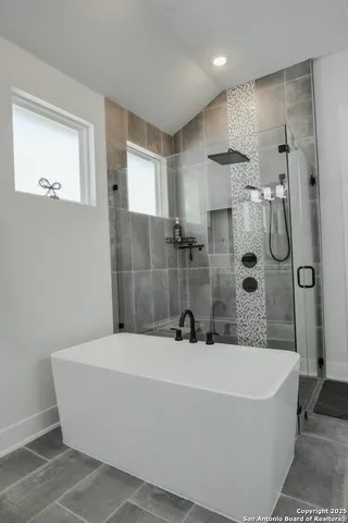 a bathroom with a tub sink mirror and shower