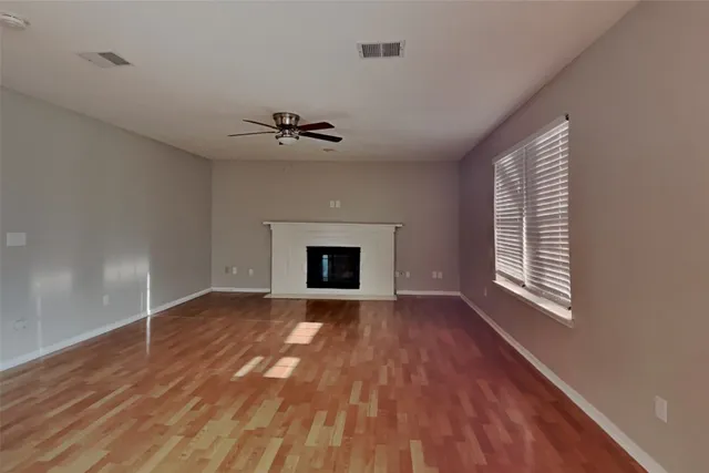 a view of an empty room with exposed radiator and a fireplace