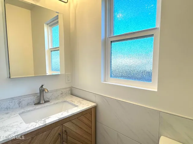 a bathroom with a granite countertop sink and a window