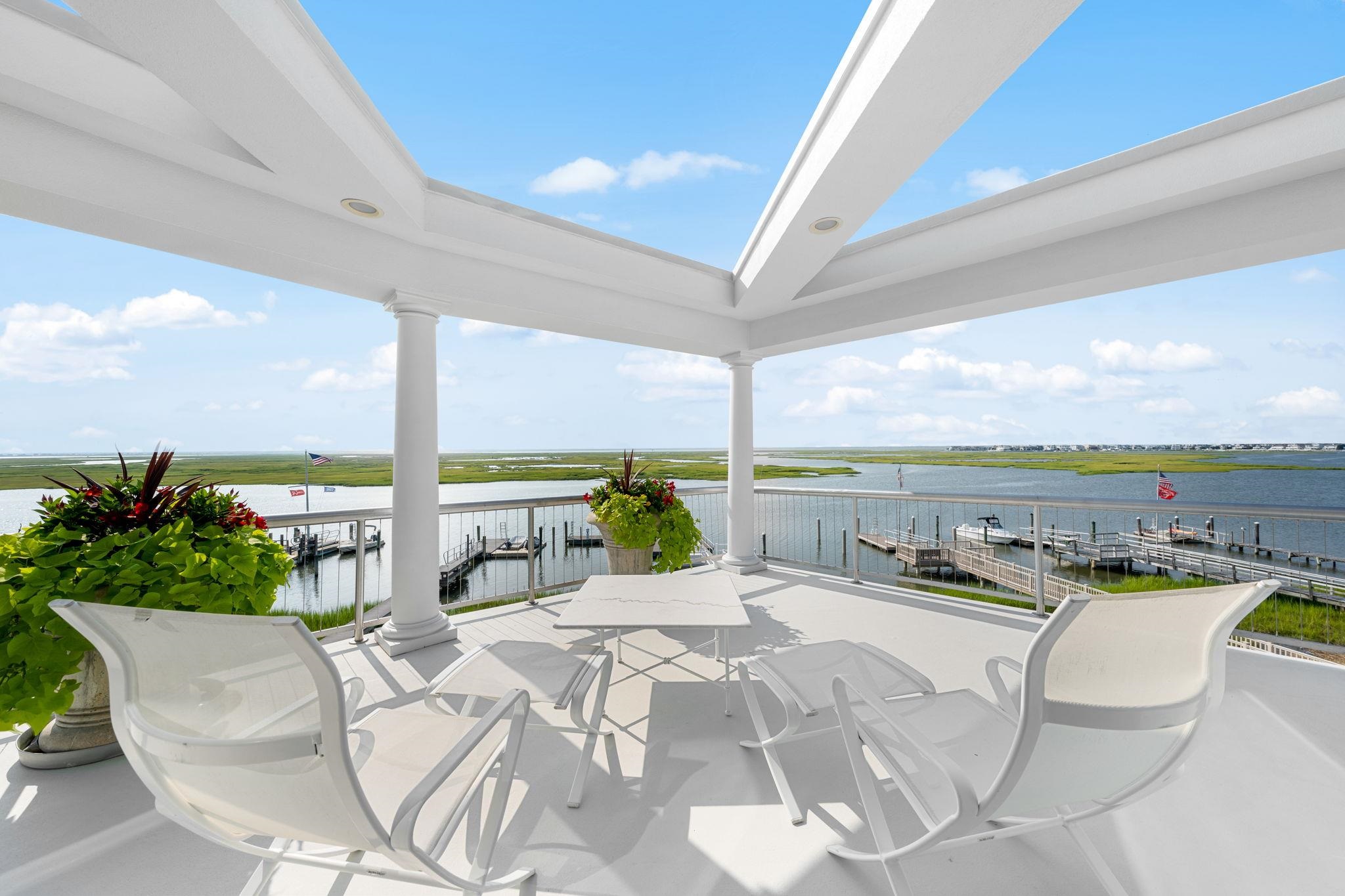5878 Ocean Drive Avalon, NJ 08202 - Photo 35 of 50 a view of a balcony with dining table and chairs with wooden floor