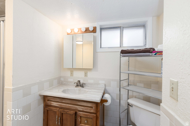 875 Patterson Street Ogden, UT 84403 - Photo 23 of 38 Bathroom with vanity, a textured wall, tile walls, and a wainscoted wall