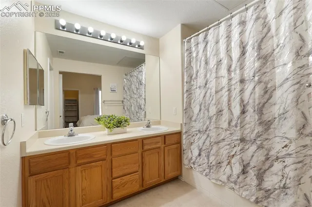 a spacious bathroom with double vanity a mirror and a shower