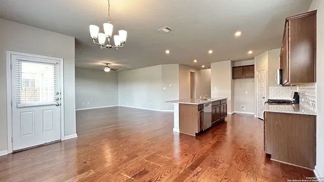 a large kitchen with a center island wooden floor and stainless steel appliances