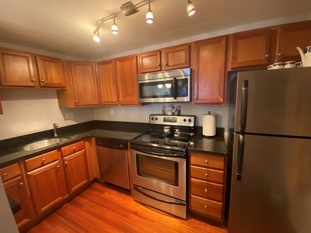 a kitchen with granite countertop a refrigerator stove top oven and sink