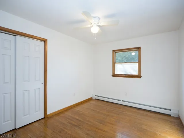 an empty room with wooden floor ceiling fan and windows