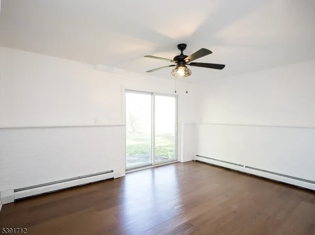an empty room with wooden floor fan and windows