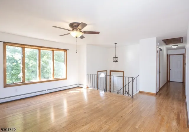 a view of an empty room with a window and wooden floor