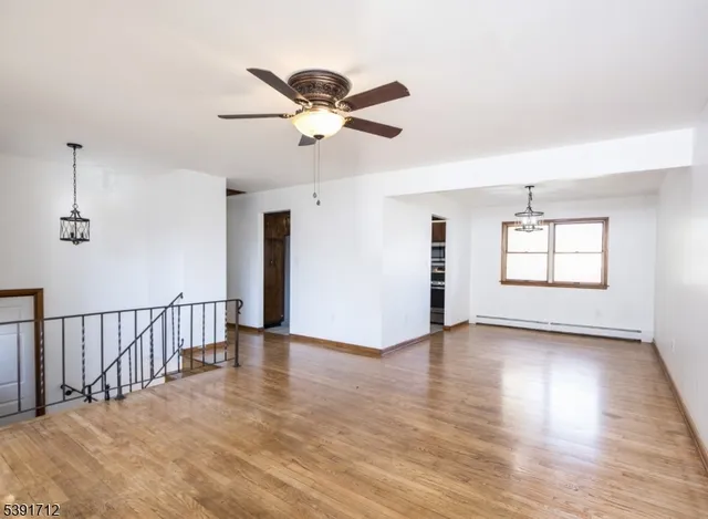 a view of an empty room with window and wooden floor