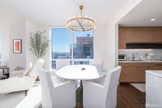 a dining room with wooden floor a chandelier a wooden table and chairs