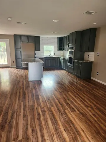 a large kitchen with stainless steel appliances wooden floors and wooden cabinets