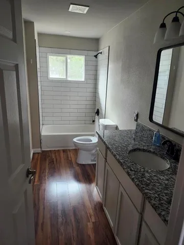 a bathroom with a granite countertop sink a toilet a mirror and shower