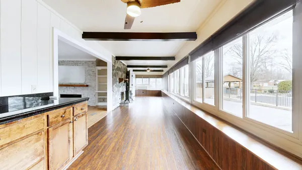 a view of an empty room with window and wooden floor