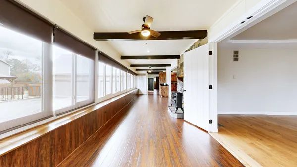 an empty room with wooden floor fan and windows