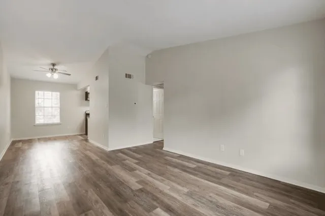 a view of empty room with wooden floor and fan