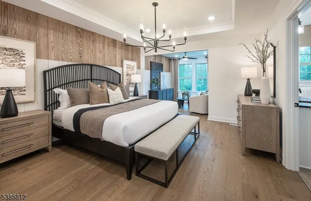 a spacious bedroom with a bed a chandelier and window