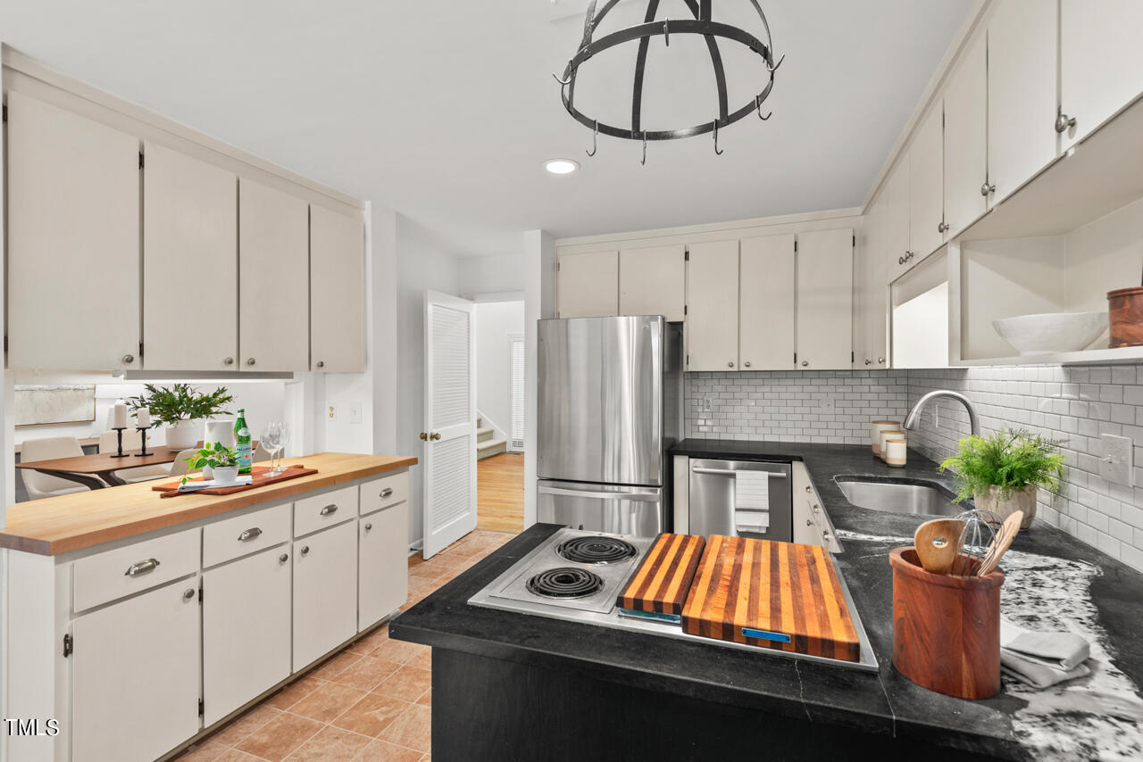 50 Stoneridge Road Durham, NC 27705 - Photo 20 of 40 a kitchen with stainless steel appliances kitchen island granite countertop a stove a sink dishwasher and white cabinets with wooden floor
