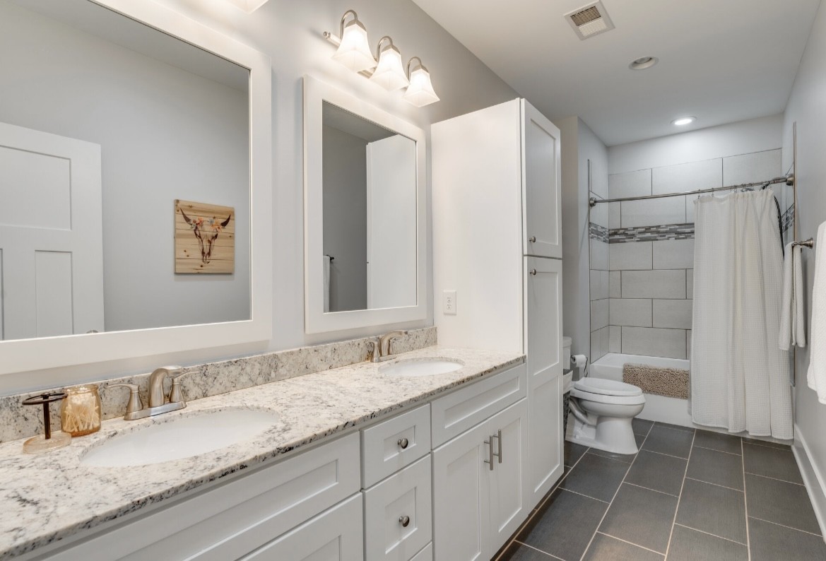 5560 Pinewood Road Franklin, TN 37064 - Photo 23 of 43 a bathroom with a granite countertop sink a toilet a shower and a mirror