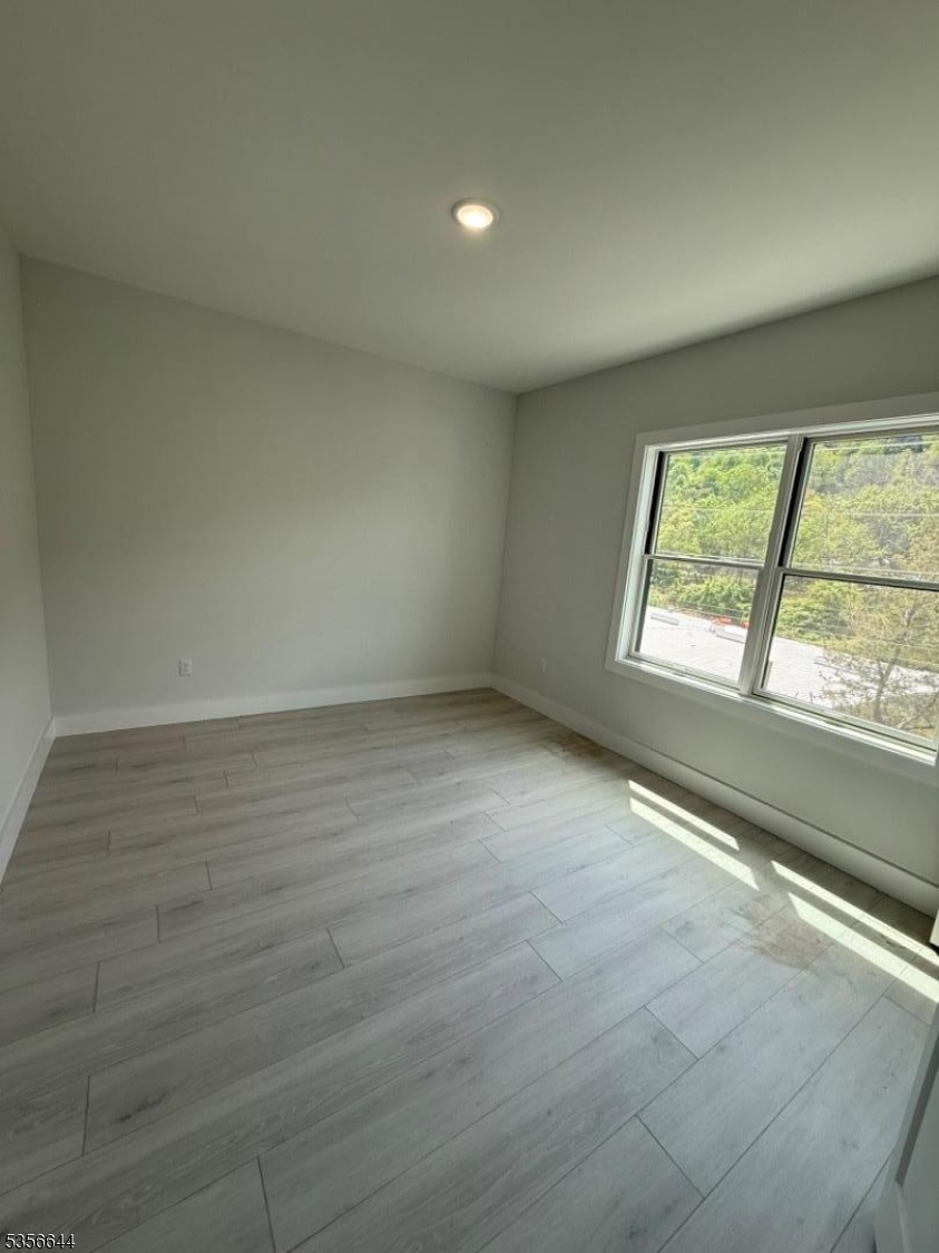261 Marshall Street, Unit 507 Paterson, NJ 07503 - Photo 11 of 14 an empty room with wooden floor and windows