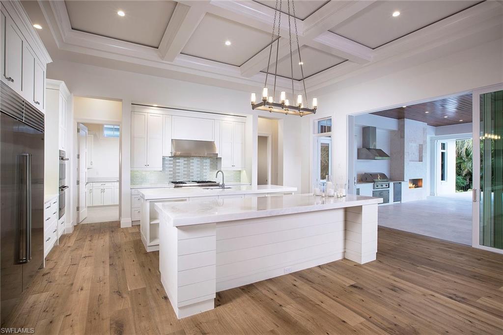 3020 Crayton Road Naples, FL 34103 - Photo 2 of 6 a large kitchen with stainless steel appliances a chandelier and wooden floors