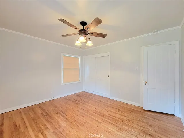 an empty room with wooden floor fan and windows