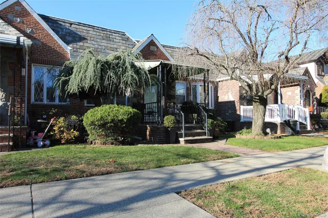 a view of a white house with a yard garden and plants