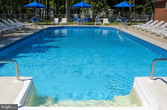 a view of swimming pool with chairs and tables under an umbrella