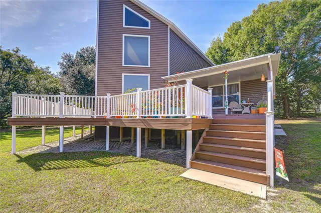 a view of a house with a yard deck and a large tree