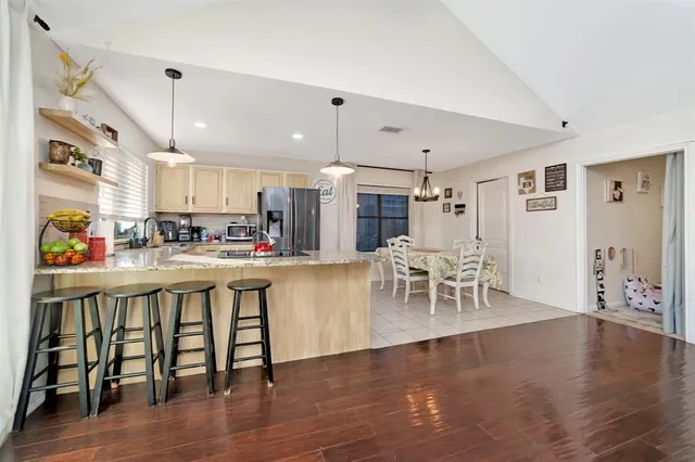 a kitchen with stainless steel appliances granite countertop a stove top oven a sink a dining table and chairs with wooden floor