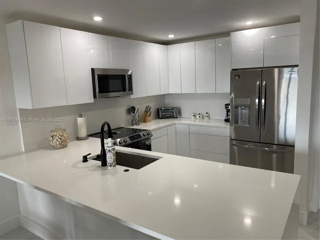 a kitchen with a sink a refrigerator and cabinets