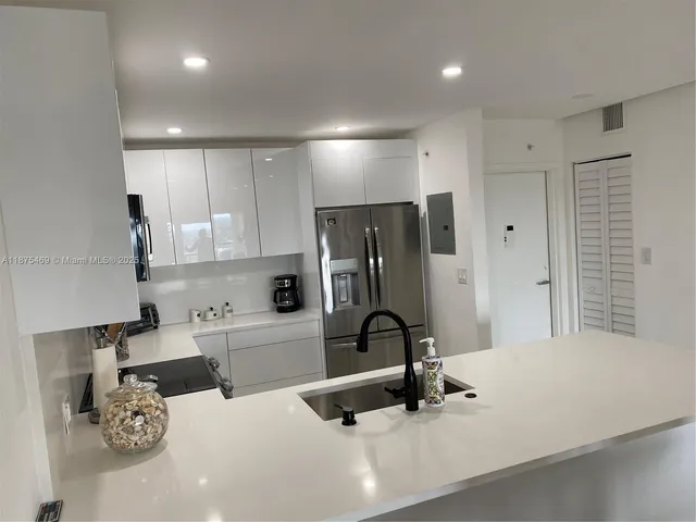 a kitchen with stainless steel appliances a sink a stove a microwave a refrigerator a white cabinets and a counter top space