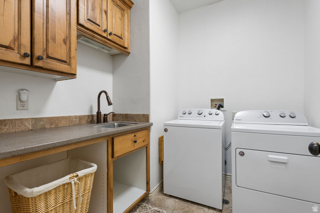 882 Sego Lily Way Mapleton, UT 84664 - Photo 12 of 41 Utility room featuring wood-finish cabinetry, a sink with a bronze-finish faucet, and a stone-finish tile backsplash