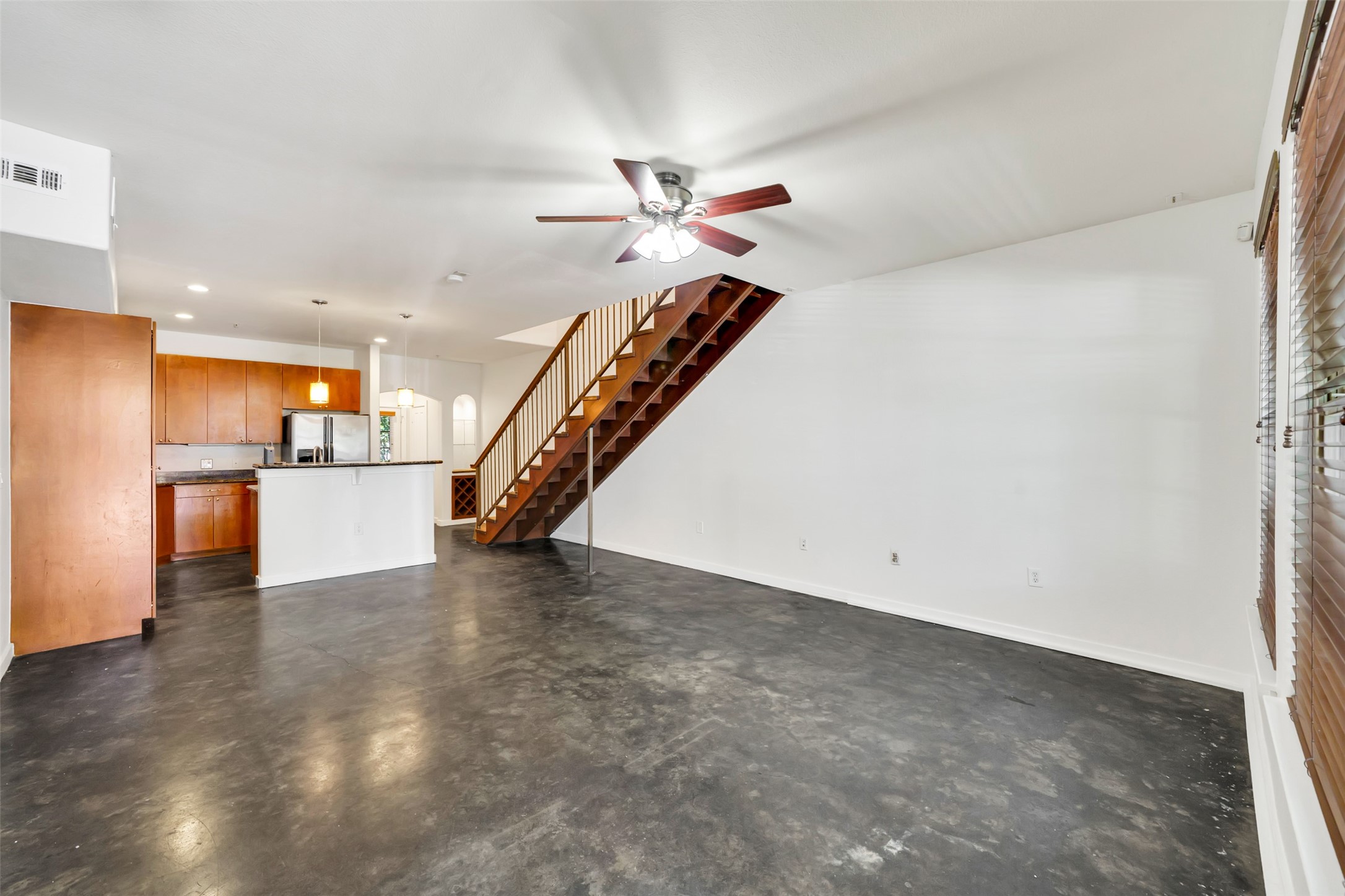 2216 Chenevert Street, Unit 6 Houston, TX 77003 - Photo 9 of 29 Striking open-concept living area featuring modern floating stairs, polished concrete floors, and a built-in bar—designed for stylish entertaining with seamless flow to the kitchen and adjacent living spaces.