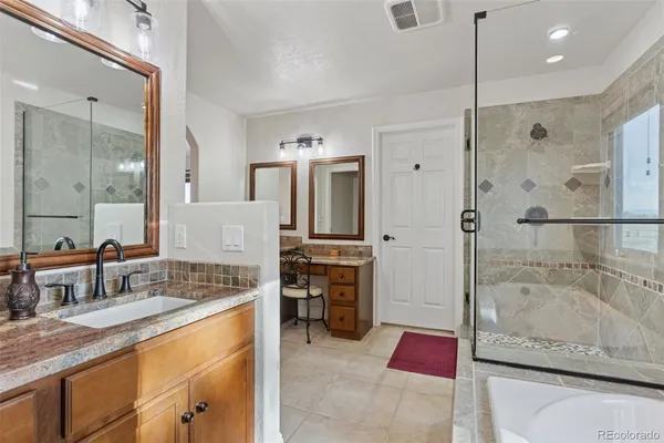 a bathroom with a granite countertop tub sink shower and mirror