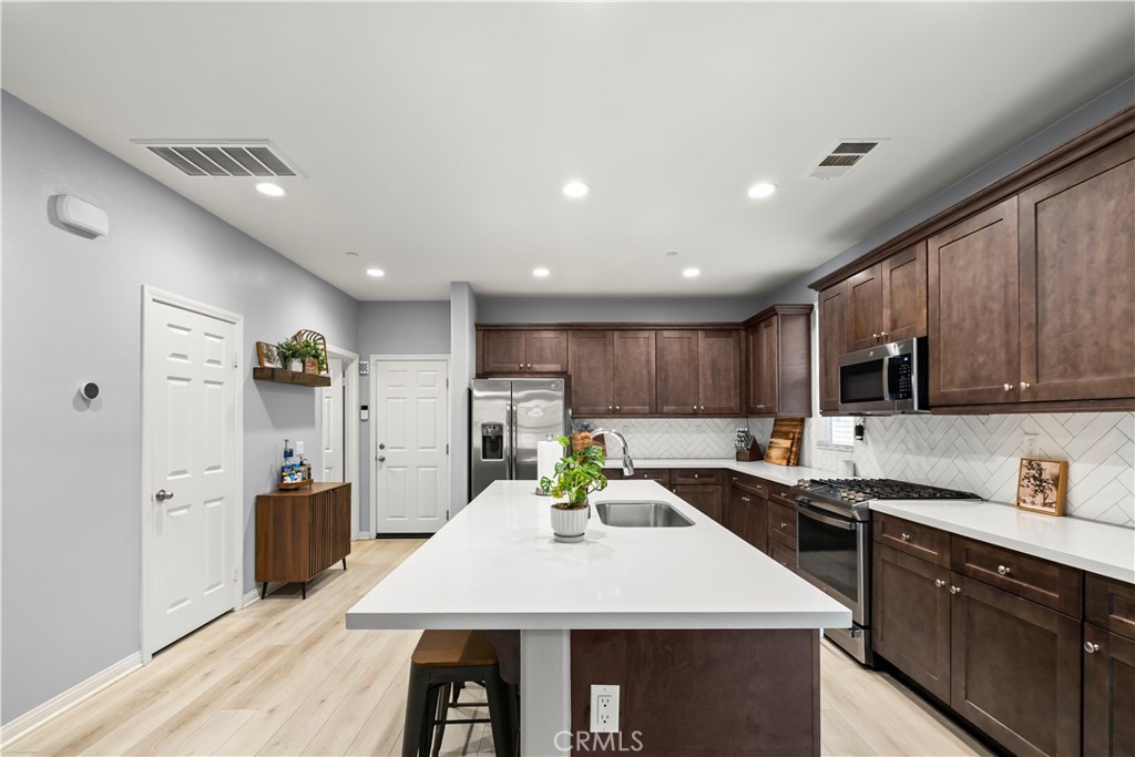 692 South Brampton Avenue Rialto, CA 92376 - Photo 4 of 21 a large kitchen with stainless steel appliances lots of counter space and wooden floor