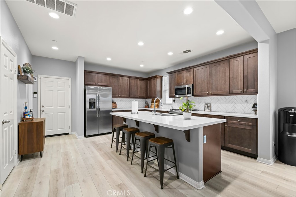 692 South Brampton Avenue Rialto, CA 92376 - Photo 5 of 21 a kitchen with stainless steel appliances granite countertop a table chairs sink refrigerator and cabinets