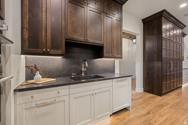 4871 South Homestead Way Washington, UT 84780 - Photo 33 of 151 Kitchen featuring light wood-style flooring, dark wood finish cabinetry, dark stone counters, decorative backsplash, and recessed lighting