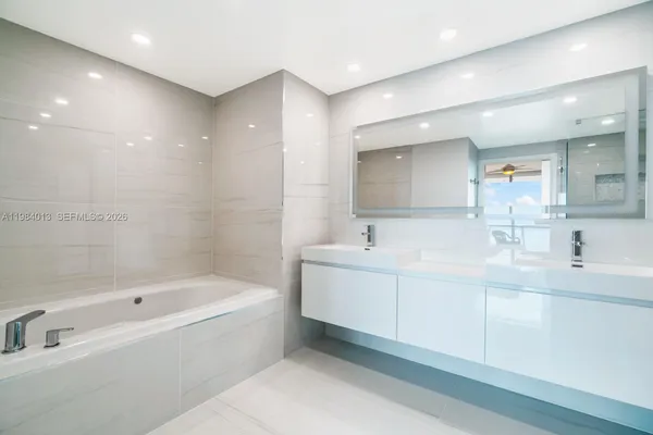 a bathroom with a bathtub a mirror a sink and vanity