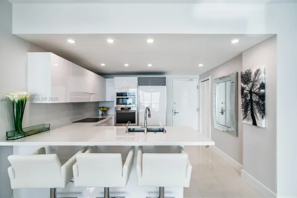 a kitchen with stainless steel appliances kitchen island granite countertop a refrigerator and a sink