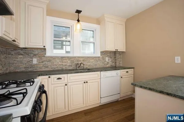 a kitchen with granite countertop a sink stove and cabinets