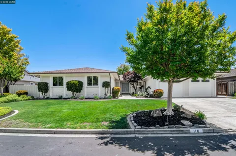 a front view of a house with a garden and trees