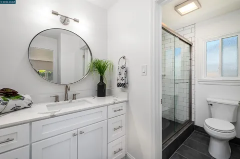 a bathroom with a toilet a sink a glass door a shower and a mirror