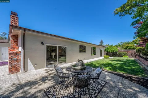 a view of a chair and table in backyard of the house