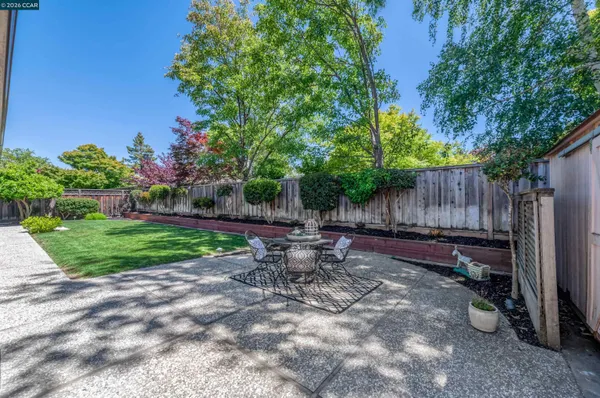a view of a backyard with table and chairs and wooden fence