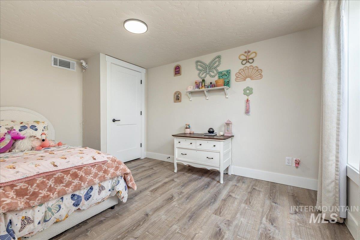 23011 Allendale Road Parma, ID 83660 - Photo 32 of 50 Wood-finish flooring, white trim, recessed ceiling light, white paneled door, and a curtained window