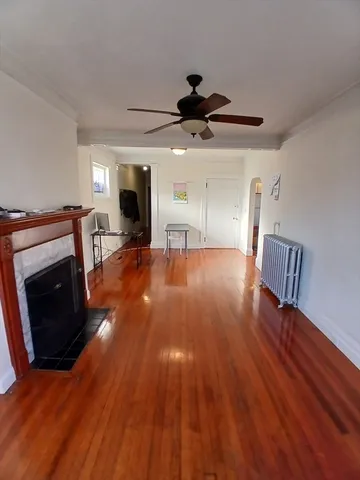 a view of an empty room with wooden floor fireplace and a window