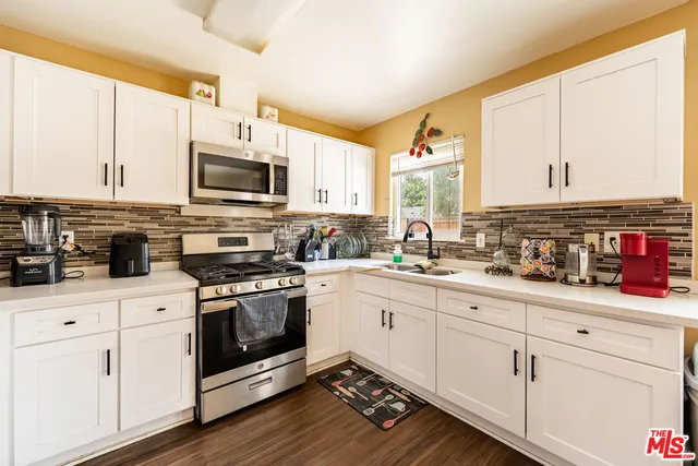a kitchen with granite countertop a refrigerator stove top oven and sink