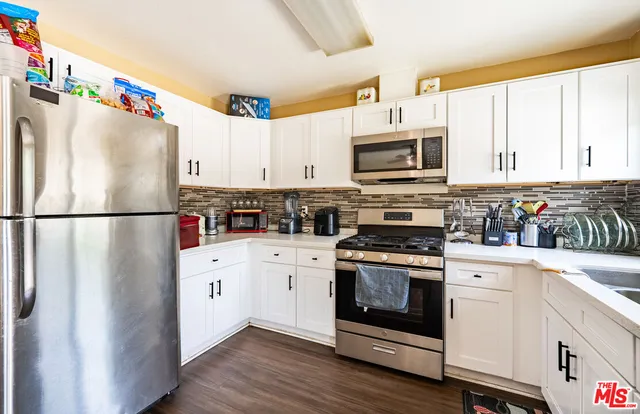 a kitchen with stainless steel appliances granite countertop a sink refrigerator dining table and chairs