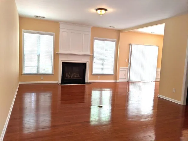 a view of a livingroom with wooden floor and a fireplace